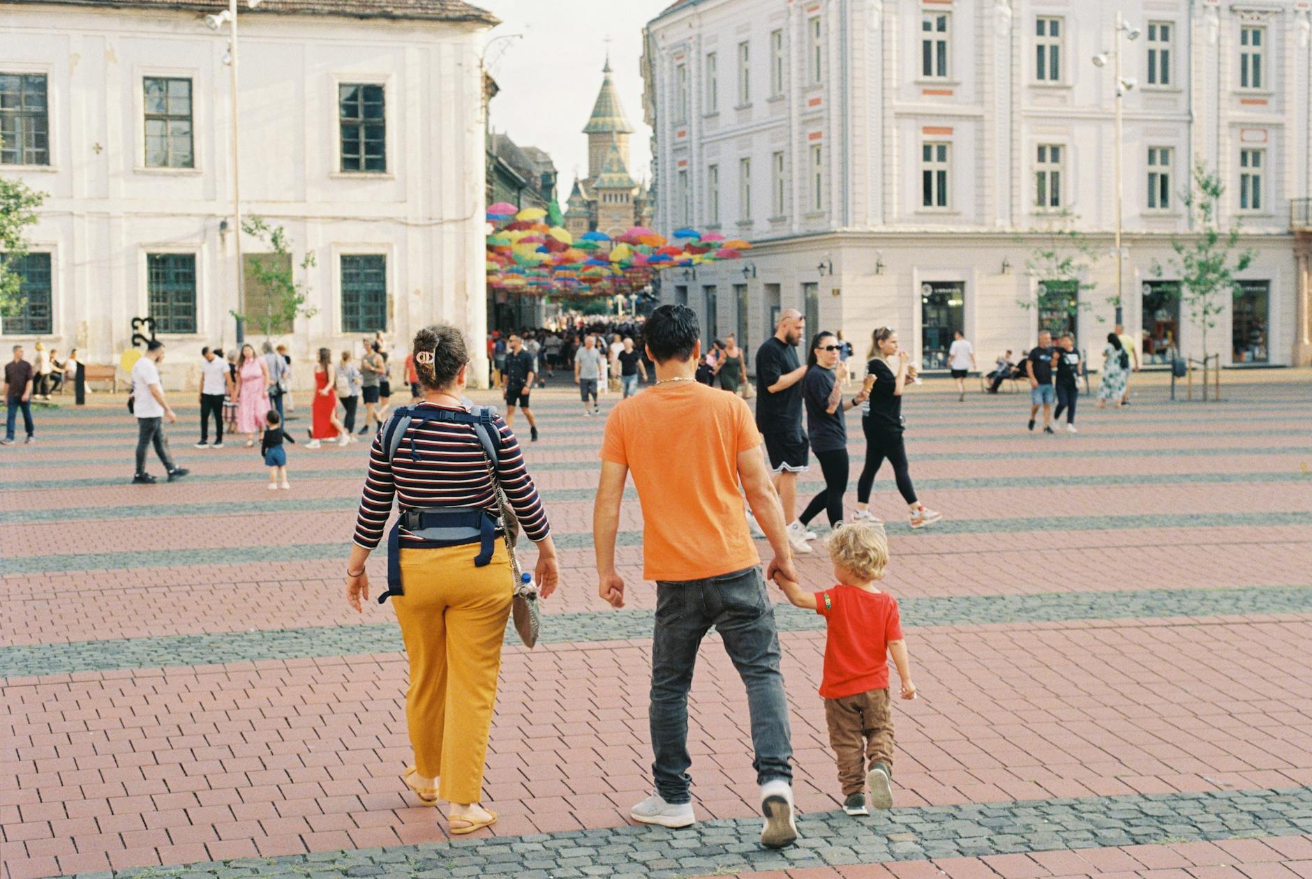 Rodzina spaceruje po kolorowym lwowskim rynku z parasolami nad głowami