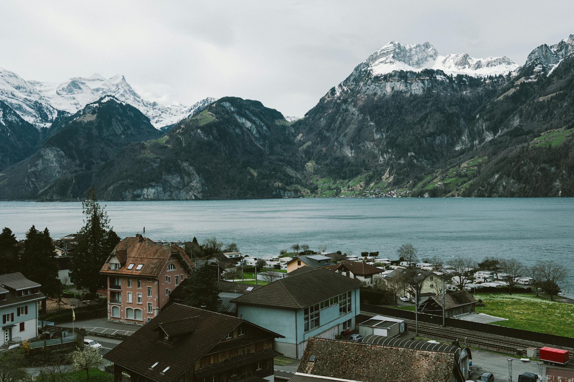 Szwajarska wioska nad jeziorem otoczona ośnieżonymi Alpami z lotu ptaka