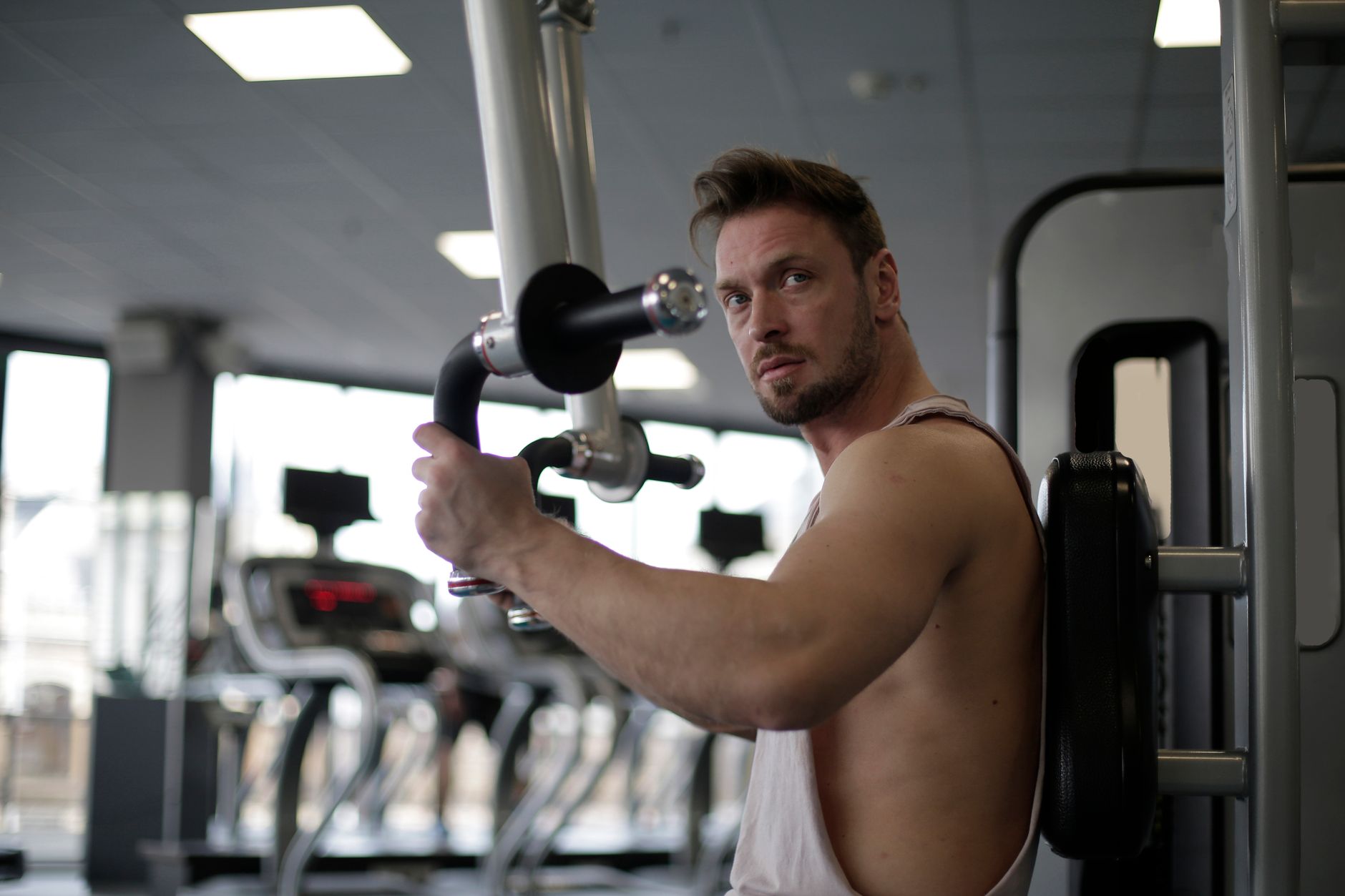 Mężczyzna ćwiczący biceps na siłowni, skupiony na treningu Mężczyzna ćwiczący biceps na siłowni, skupiony na treningu