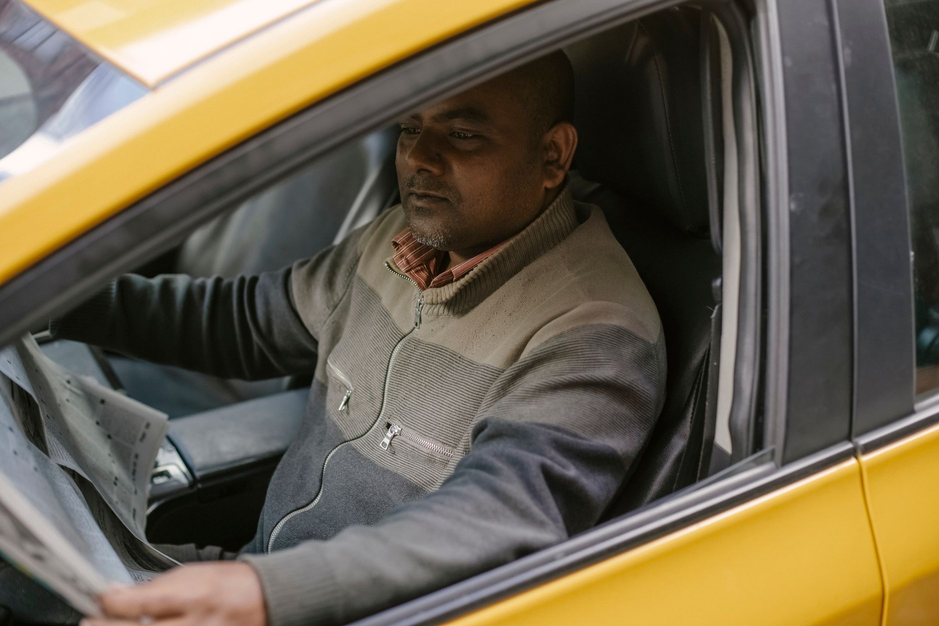 Kierowca taxi czytający gazetę podczas przerwy w zaparkowanym aucie