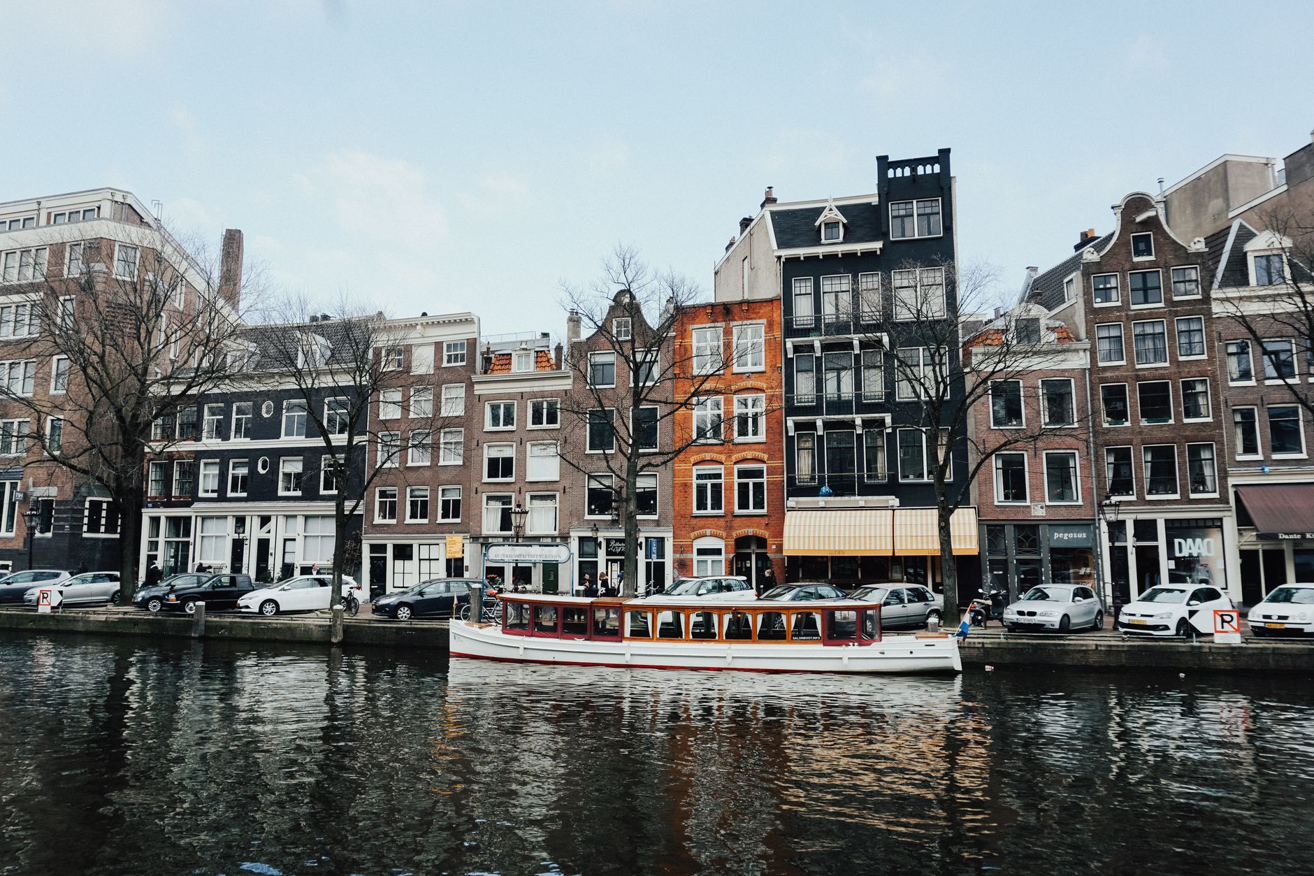 Kanał w Amsterdamie z łodzią i tradycyjnymi kamienicami nad wodą